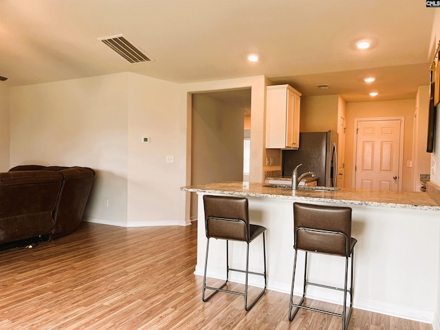 1406 Native Garden Rd, Gilbert, SC 29054 - kitchen with freestanding refrigerator, light wood-style floors, a breakfast bar, light stone counters, and a peninsula