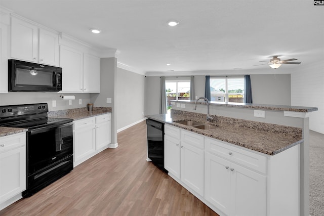 239 Common Reed Dr, Gilbert, SC 29054 - kitchen with black appliances, white cabinetry, light wood-style floors, light stone counters, and a center island with sink