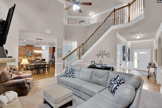 699 Village Market Dr, Chapin, SC 29036 - living room featuring light wood-type flooring, stairway, ornamental molding, a ceiling fan, and a towering ceiling