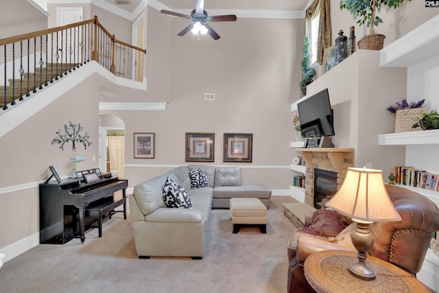 699 Village Market Dr, Chapin, SC 29036 - carpeted living room featuring a ceiling fan, a towering ceiling, a stone fireplace, stairs, and arched walkways