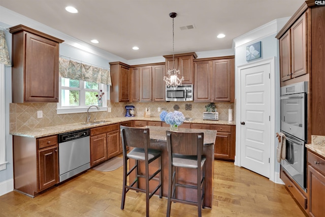 699 Village Market Dr, Chapin, SC 29036 - kitchen featuring stainless steel appliances, light wood-style flooring, a kitchen breakfast bar, light stone countertops, and recessed lighting
