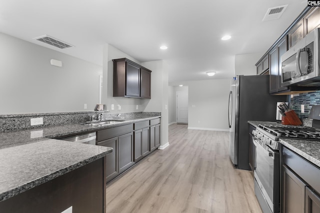 465 Vanburen Ct, Gaston, SC 29053 - kitchen with gas range, stainless steel microwave, light wood-type flooring, decorative backsplash, and dark stone counters