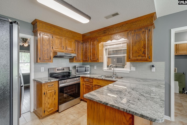 40 Stonehedge Ct, Sumter, SC 29154 - kitchen featuring appliances with stainless steel finishes, under cabinet range hood, a peninsula, brown cabinetry, and decorative backsplash