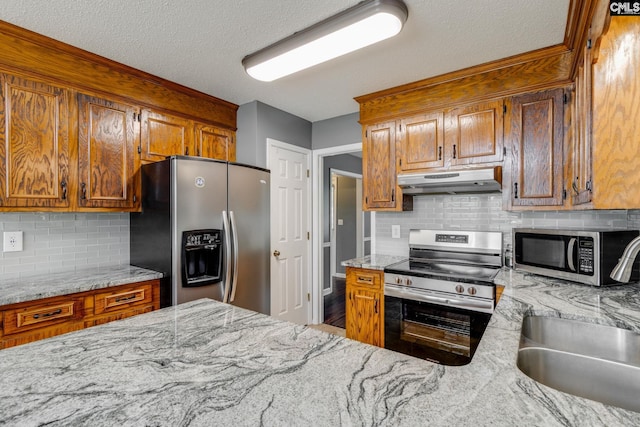 40 Stonehedge Ct, Sumter, SC 29154 - kitchen featuring stainless steel appliances, under cabinet range hood, decorative backsplash, light stone countertops, and brown cabinets