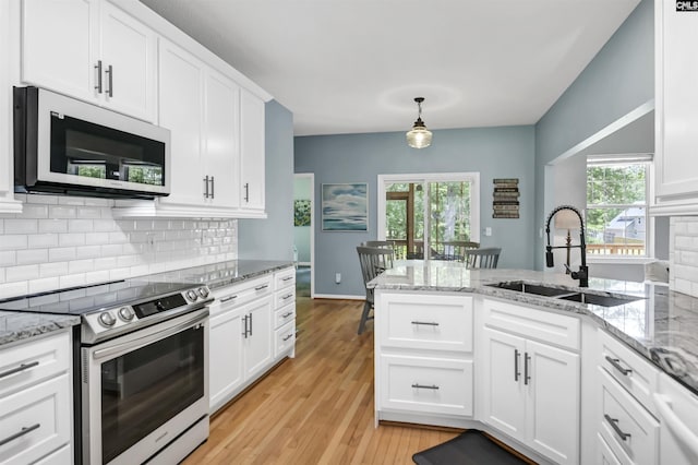 1040 Night Harbor Cir, Chapin, SC 29036 - kitchen with appliances with stainless steel finishes, white cabinets, tasteful backsplash, a peninsula, and light wood finished floors