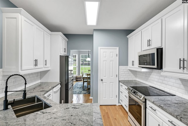 1040 Night Harbor Cir, Chapin, SC 29036 - kitchen featuring stainless steel appliances, white cabinetry, light wood-style flooring, and light stone countertops