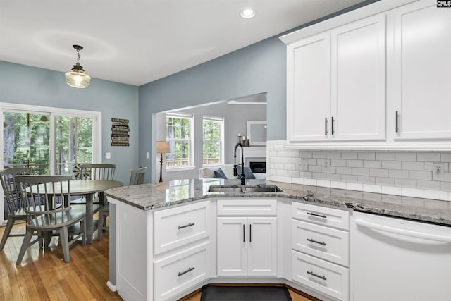 1040 Night Harbor Cir, Chapin, SC 29036 - kitchen with dishwasher, a peninsula, light wood finished floors, backsplash, and light stone counters