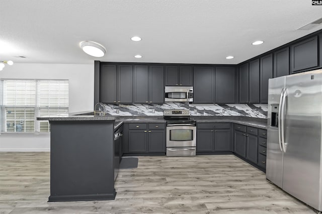 339 Bracken Dr, Lexington, SC 29072 - kitchen with appliances with stainless steel finishes, a peninsula, dark countertops, light wood finished floors, and recessed lighting
