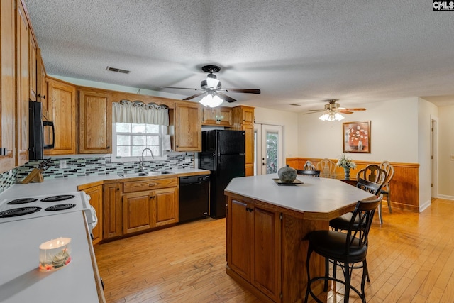 1162 Whippoorwill Rd, Camden, SC 29020 - kitchen featuring black appliances, a breakfast bar, light wood-type flooring, a center island, and light countertops