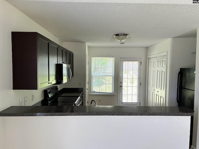 206 Windsor Village Dr, Columbia, SC 29223 - kitchen featuring black appliances, a peninsula, dark countertops, and a textured ceiling