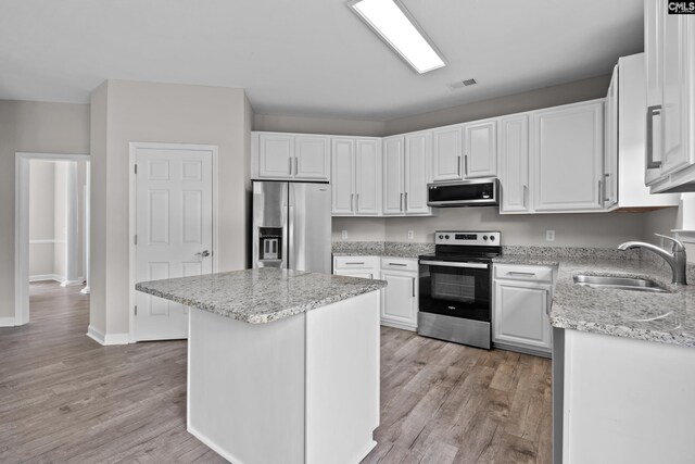 2 Alverston Ct, Irmo, SC 29063 - kitchen featuring appliances with stainless steel finishes, white cabinetry, light wood finished floors, a kitchen island, and light stone counters