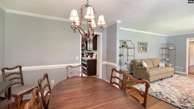6965 Shelley Rd, Columbia, SC 29209 - dining room featuring wood finished floors, crown molding, a chandelier, and a textured ceiling