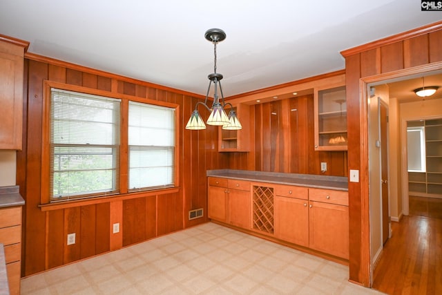 1120 Garden Ave, Cayce, SC 29033 - kitchen featuring wooden walls, pendant lighting, brown cabinets, and glass insert cabinets