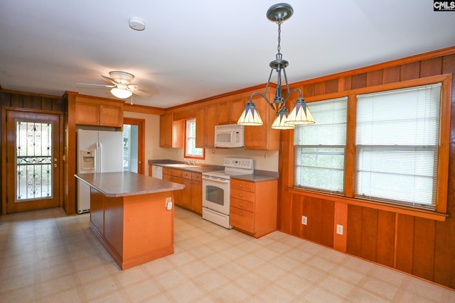 1120 Garden Ave, Cayce, SC 29033 - kitchen featuring white appliances, wooden walls, a center island, light flooring, and decorative light fixtures