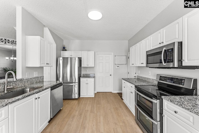218 Founders Ridge Rd, Columbia, SC 29229 - kitchen with stainless steel appliances, a textured ceiling, light wood-style flooring, white cabinets, and dark stone counters