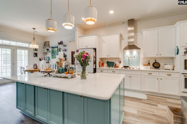 6150 Crabtree Rd, Columbia, SC 29206 - kitchen with wall chimney exhaust hood, freestanding refrigerator, gas stovetop, white cabinets, and light countertops
