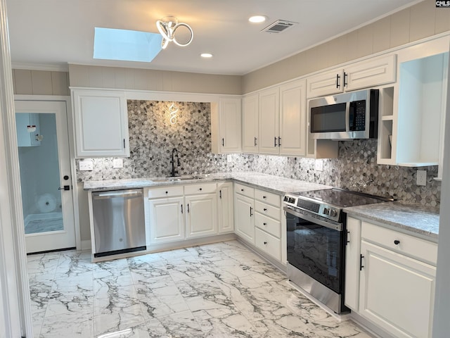 1341 Sanford Rd, Columbia, SC 29206 - kitchen with stainless steel appliances, a skylight, light marble finish flooring, backsplash, and white cabinets