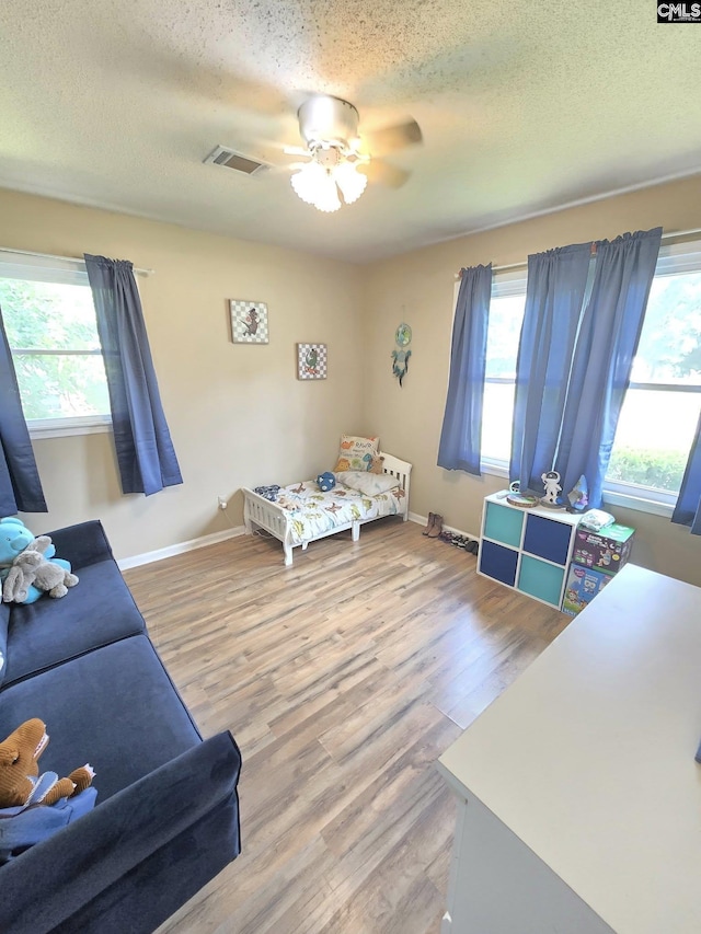 704 Cambridge, Lugoff, SC 29078 - bedroom with multiple windows, light wood finished floors, a textured ceiling, and a ceiling fan