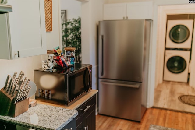 39 Downing, Columbia, SC 29209 - kitchen with freestanding refrigerator, estacked washer and dryer, black microwave, light wood-type flooring, and white cabinetry