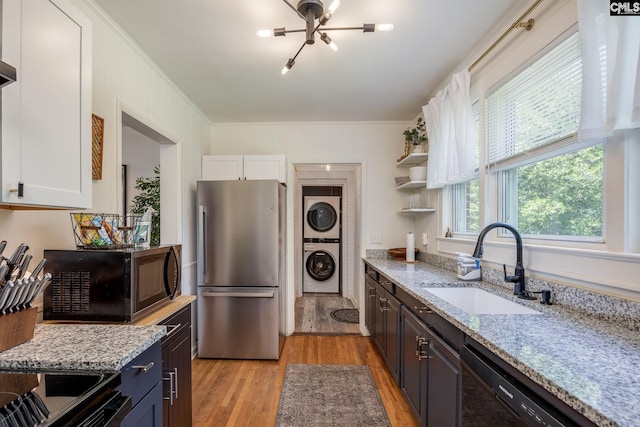 39 Downing, Columbia, SC 29209 - kitchen featuring freestanding refrigerator, stacked washer / dryer, black microwave, white cabinets, and ornamental molding
