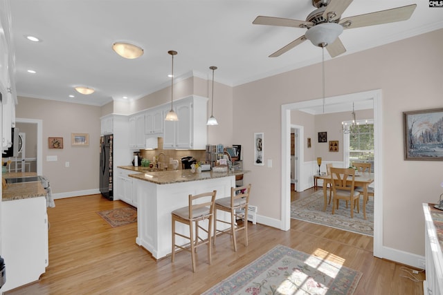 8 Sand Spur Rd, Columbia, SC 29223 - kitchen with white cabinets, freestanding refrigerator, a kitchen bar, light stone countertops, and crown molding