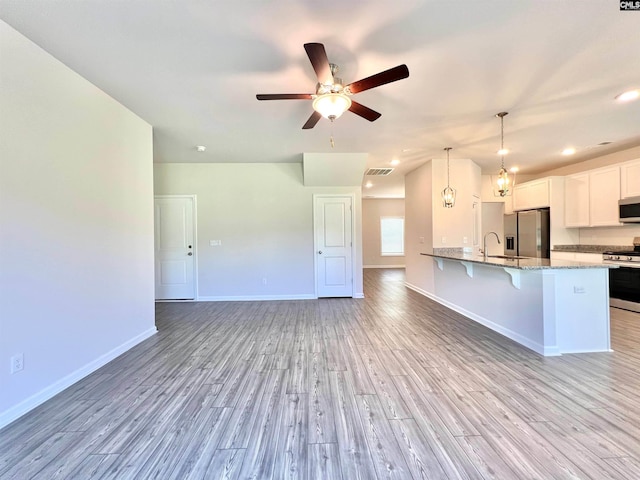 1958 Castlerock Dr, Sumter, SC 29153 - kitchen featuring stainless steel appliances, a breakfast bar, light wood finished floors, light stone counters, and white cabinetry
