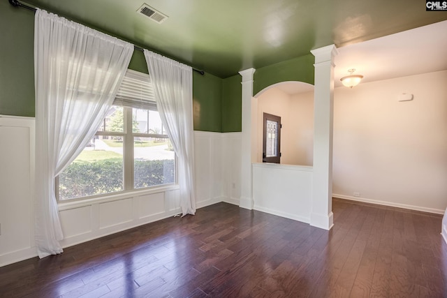 22 Kentucky Derby Ct, Lugoff, SC 29078 - spare room featuring arched walkways, dark wood-type flooring, a wainscoted wall, decorative columns, and a decorative wall