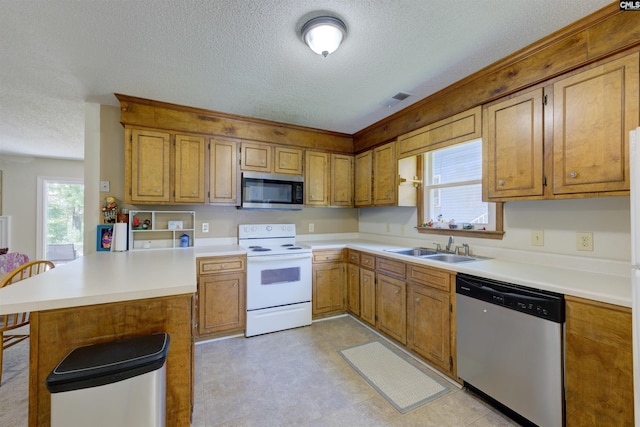 241 Friarsgate Blvd, Irmo, SC 29063 - kitchen with stainless steel appliances, a peninsula, a textured ceiling, light countertops, and brown cabinetry