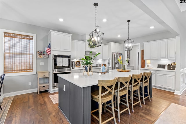 214 Chapin Brook Ct, Chapin, SC 29036 - kitchen featuring stainless steel appliances, dark wood-style floors, a center island with sink, light countertops, and white cabinetry