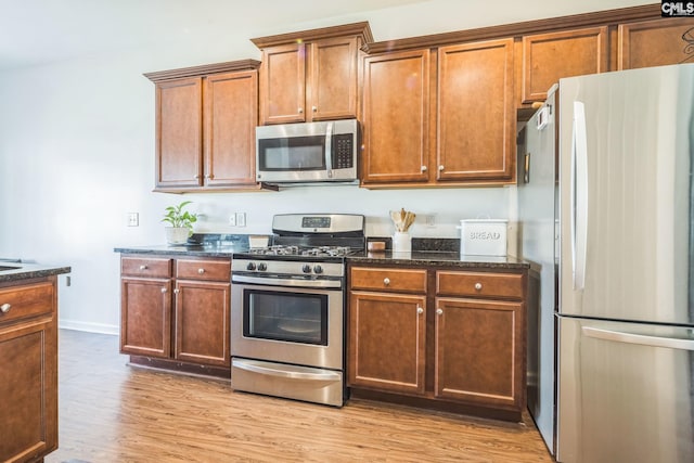 512 Eagles Rest Dr, Chapin, SC 29036 - kitchen featuring appliances with stainless steel finishes, light wood finished floors, dark stone countertops, and brown cabinets