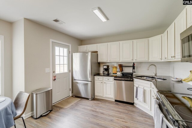 938 Farnsworth Dr, Hopkins, SC 29061 - kitchen featuring stainless steel appliances, tasteful backsplash, light wood-type flooring, white cabinetry, and dark stone counters