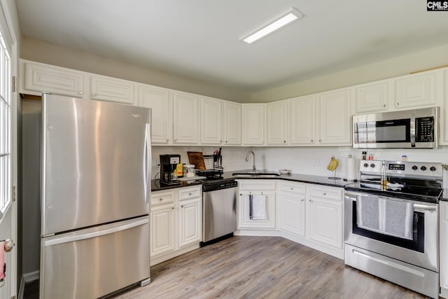 938 Farnsworth Dr, Hopkins, SC 29061 - kitchen featuring appliances with stainless steel finishes, dark countertops, light wood finished floors, and white cabinets