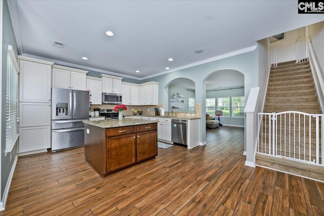 620 Blue Ledge Cir, Lexington, SC 29072 - kitchen with stainless steel appliances, ornamental molding, white cabinets, dark wood-style floors, and a kitchen island