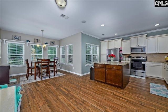 620 Blue Ledge Cir, Lexington, SC 29072 - kitchen featuring appliances with stainless steel finishes, decorative backsplash, dark wood finished floors, a center island, and ornamental molding