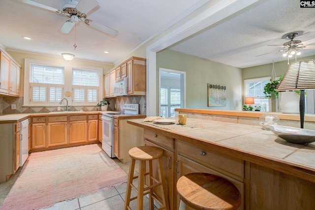 2817 Duncan St, Columbia, SC 29205 - kitchen with white appliances, ceiling fan, tile countertops, a breakfast bar, and decorative backsplash