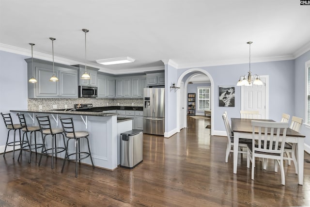 3722 Heyward St, Columbia, SC 29205 - kitchen featuring appliances with stainless steel finishes, a peninsula, gray cabinets, decorative backsplash, and ornamental molding