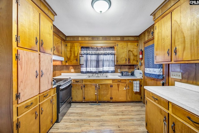 3204 Windmill Rd, Leesville, SC 29070 - kitchen featuring stainless steel range with electric stovetop, under cabinet range hood, light wood finished floors, brown cabinetry, and a textured ceiling