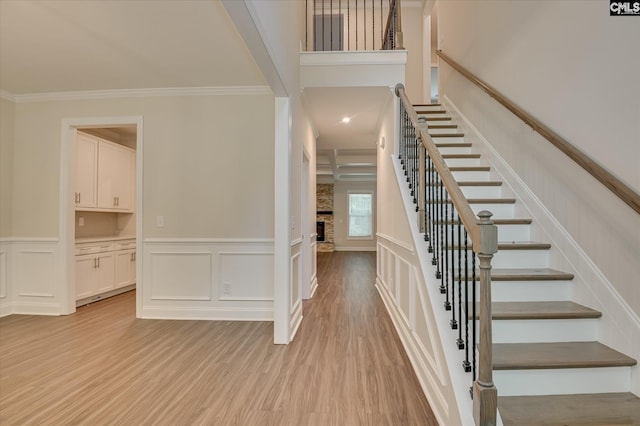 20 Belfast Ct, North Augusta, SC 29860 - stairs with a large fireplace, crown molding, wood finished floors, a decorative wall, and wainscoting