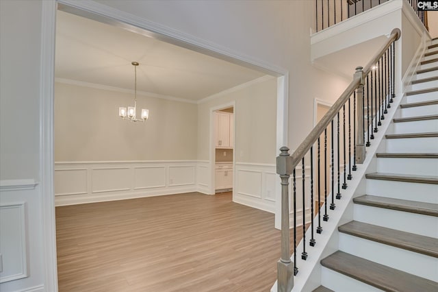 20 Belfast Ct, North Augusta, SC 29860 - staircase with a chandelier, crown molding, wood finished floors, a decorative wall, and a wainscoted wall
