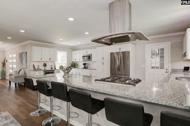 1601 Hagood Ave, Columbia, SC 29204 - kitchen featuring stainless steel appliances, island exhaust hood, light stone counters, a peninsula, and white cabinets