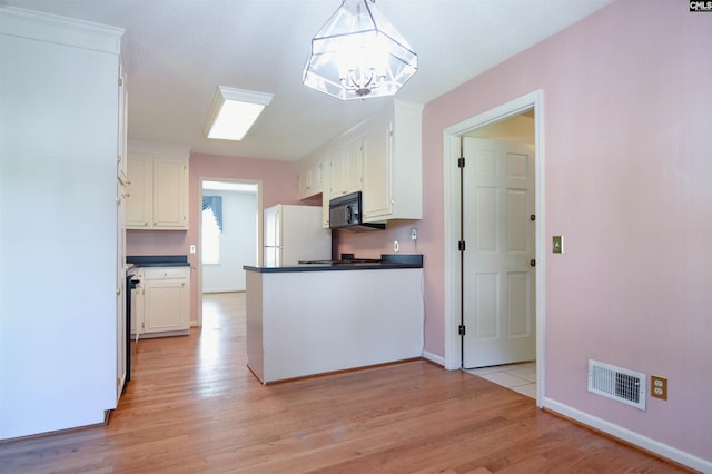 2115 Ohara Ct, Columbia, SC 29204 - kitchen featuring freestanding refrigerator, black microwave, dark countertops, light wood-style floors, and a chandelier
