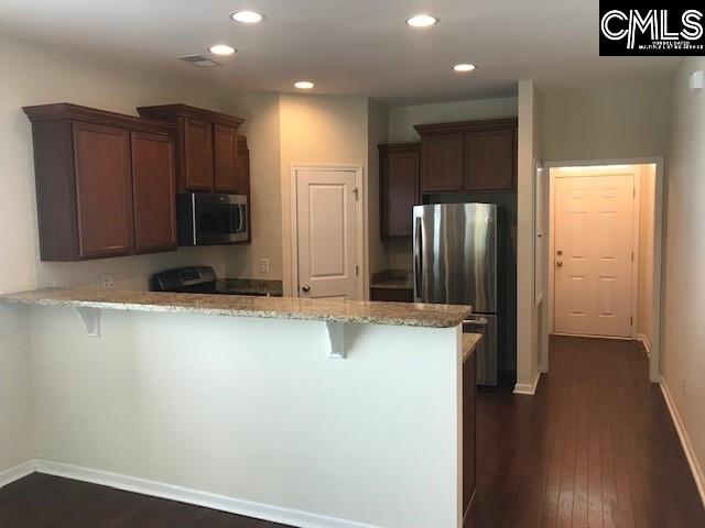532 Slices Way, Chapin, SC 29036 - kitchen featuring stainless steel appliances, a peninsula, dark wood-type flooring, light stone countertops, and a kitchen bar