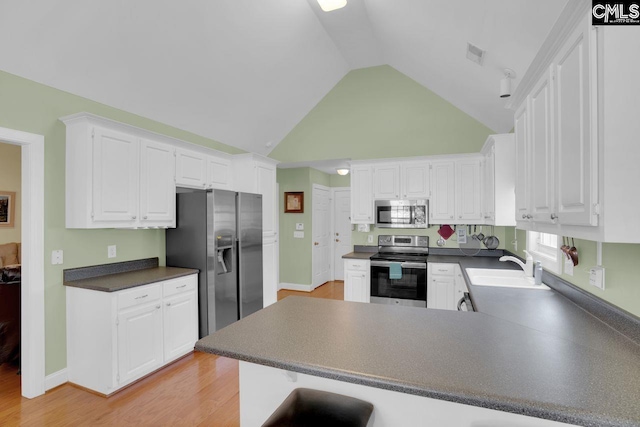 430 Plantation Pointe Dr, Elgin, SC 29045 - kitchen with stainless steel appliances, a peninsula, dark countertops, white cabinets, and high vaulted ceiling