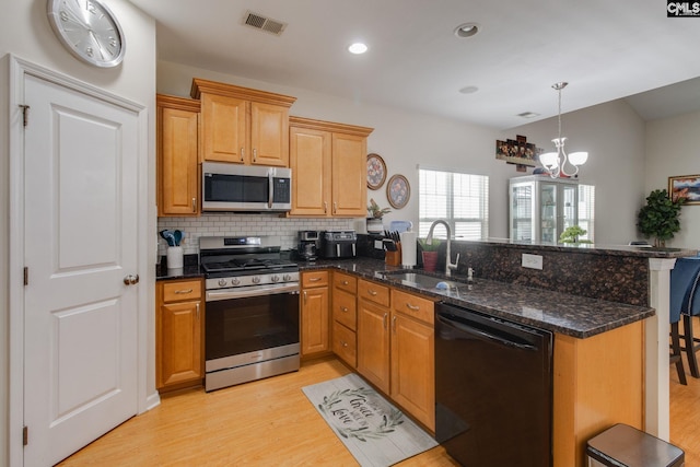 157 Autumn Stroll Ct, Lexington, SC 29072 - kitchen with stainless steel appliances, a peninsula, decorative backsplash, light wood finished floors, and dark stone countertops