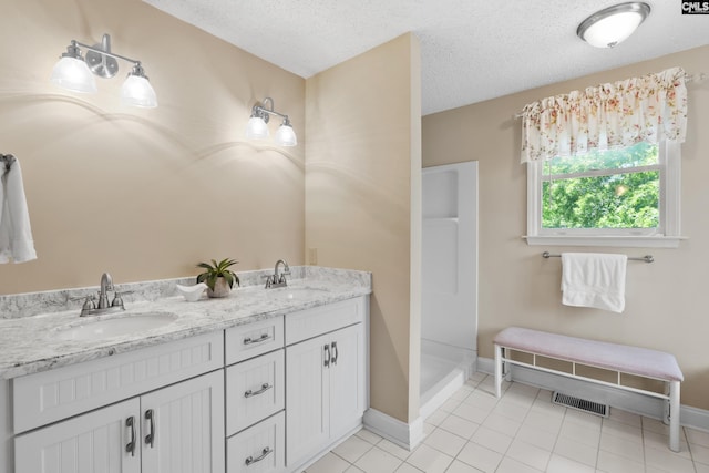 623 Hook Ave, West Columbia, SC 29169 - bathroom featuring a textured ceiling, tile patterned floors, double vanity, and a shower