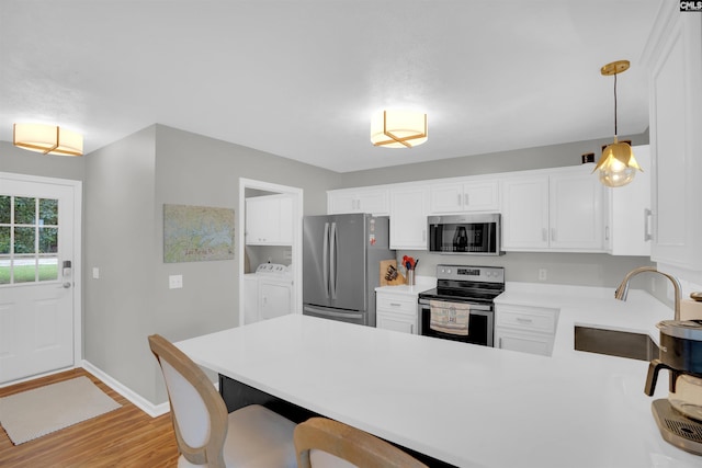 116 Laurel Rock Pt, Leesville, SC 29070 - kitchen featuring stainless steel appliances, washer and clothes dryer, a peninsula, light countertops, and light wood-style flooring