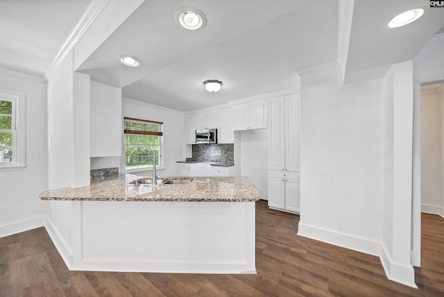 1005 D Ave, West Columbia, SC 29169 - kitchen with stainless steel microwave, ornamental molding, white cabinets, light stone countertops, and a peninsula
