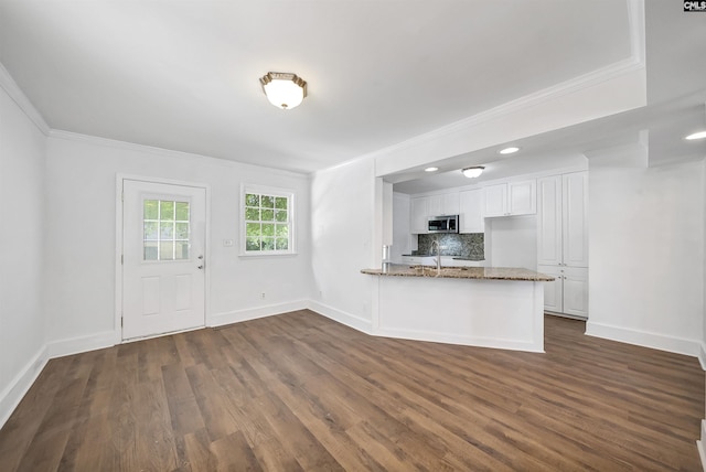 1005 D Ave, West Columbia, SC 29169 - kitchen with stainless steel microwave, crown molding, stone countertops, white cabinetry, and a peninsula