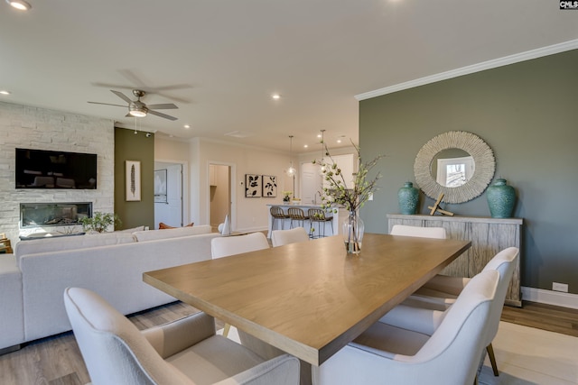 821 Oak Valley Dr, Blythewood, SC 29016 - dining space featuring light wood-style flooring, a ceiling fan, ornamental molding, recessed lighting, and a stone fireplace