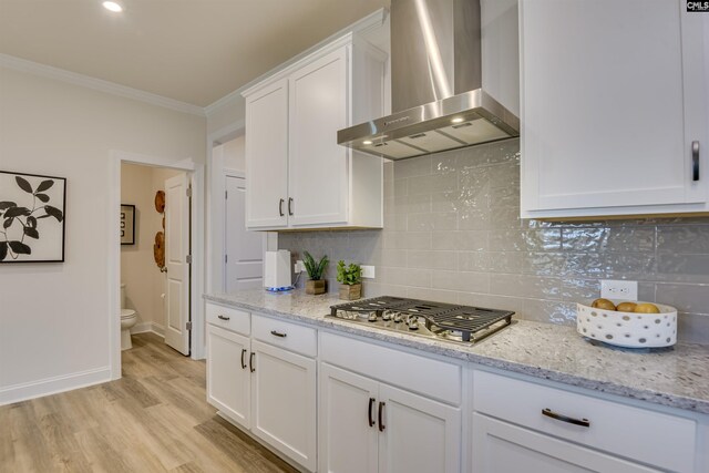821 Oak Valley Dr, Blythewood, SC 29016 - kitchen with wall chimney range hood, stainless steel gas cooktop, ornamental molding, white cabinets, and light wood finished floors